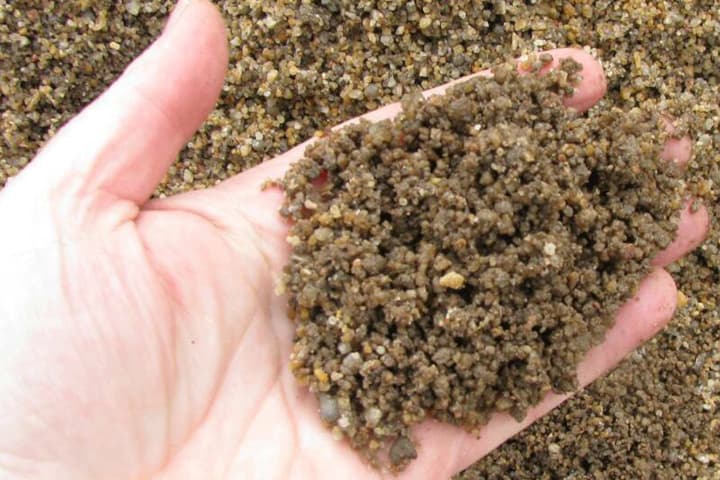 Imagen de mano con arena de río lavada